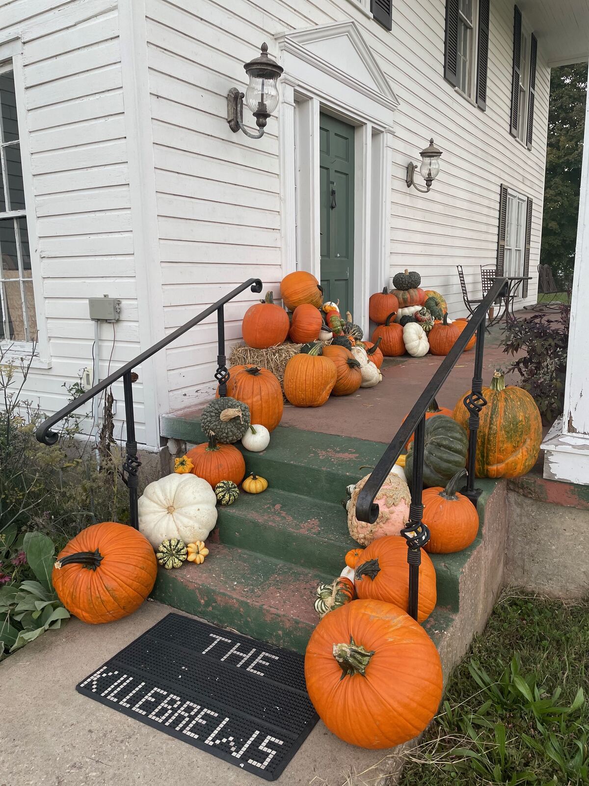 A tall arrangement of pumpkins beside a painted front door